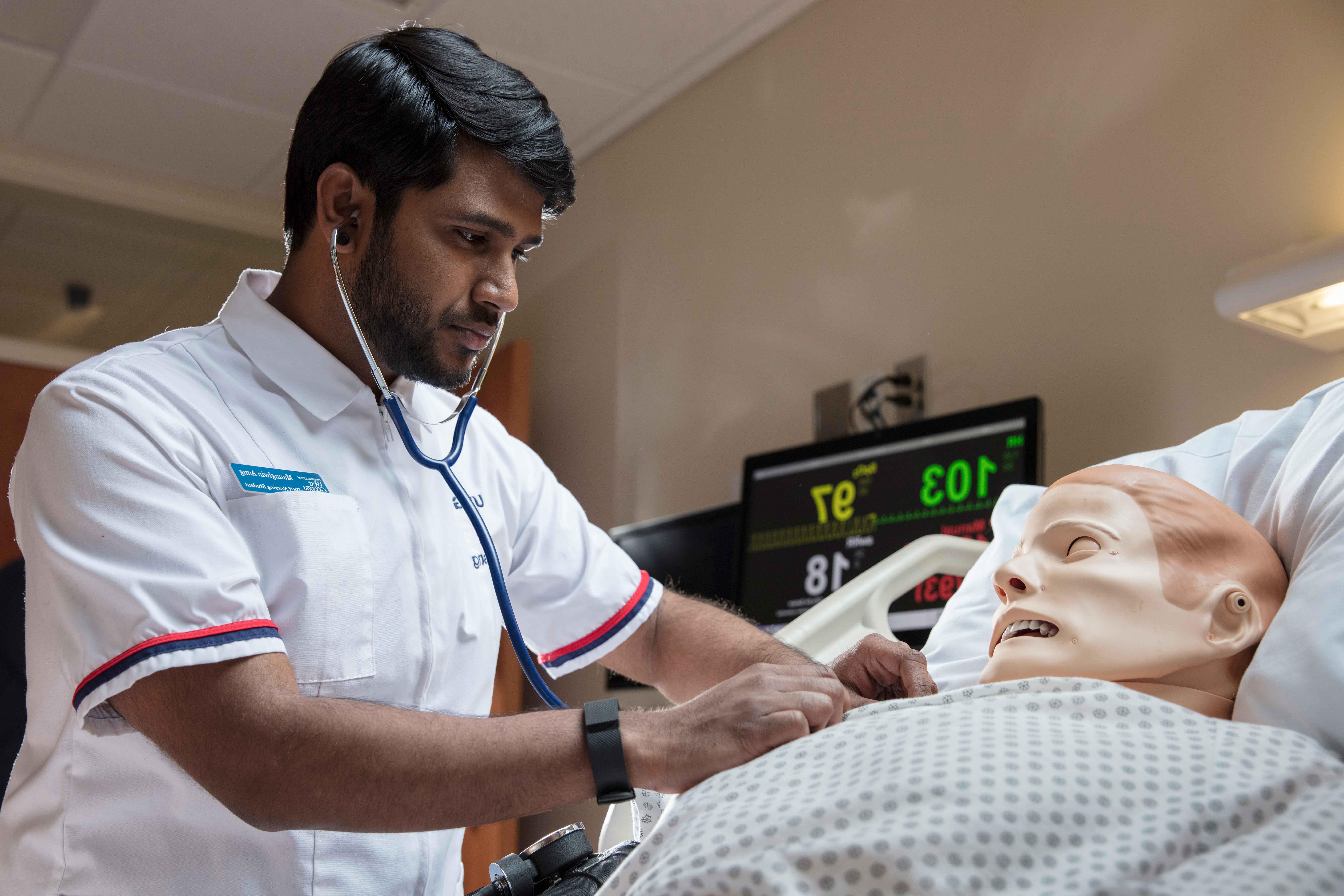 Nursing student working with an artificial patient in a simulation lab.