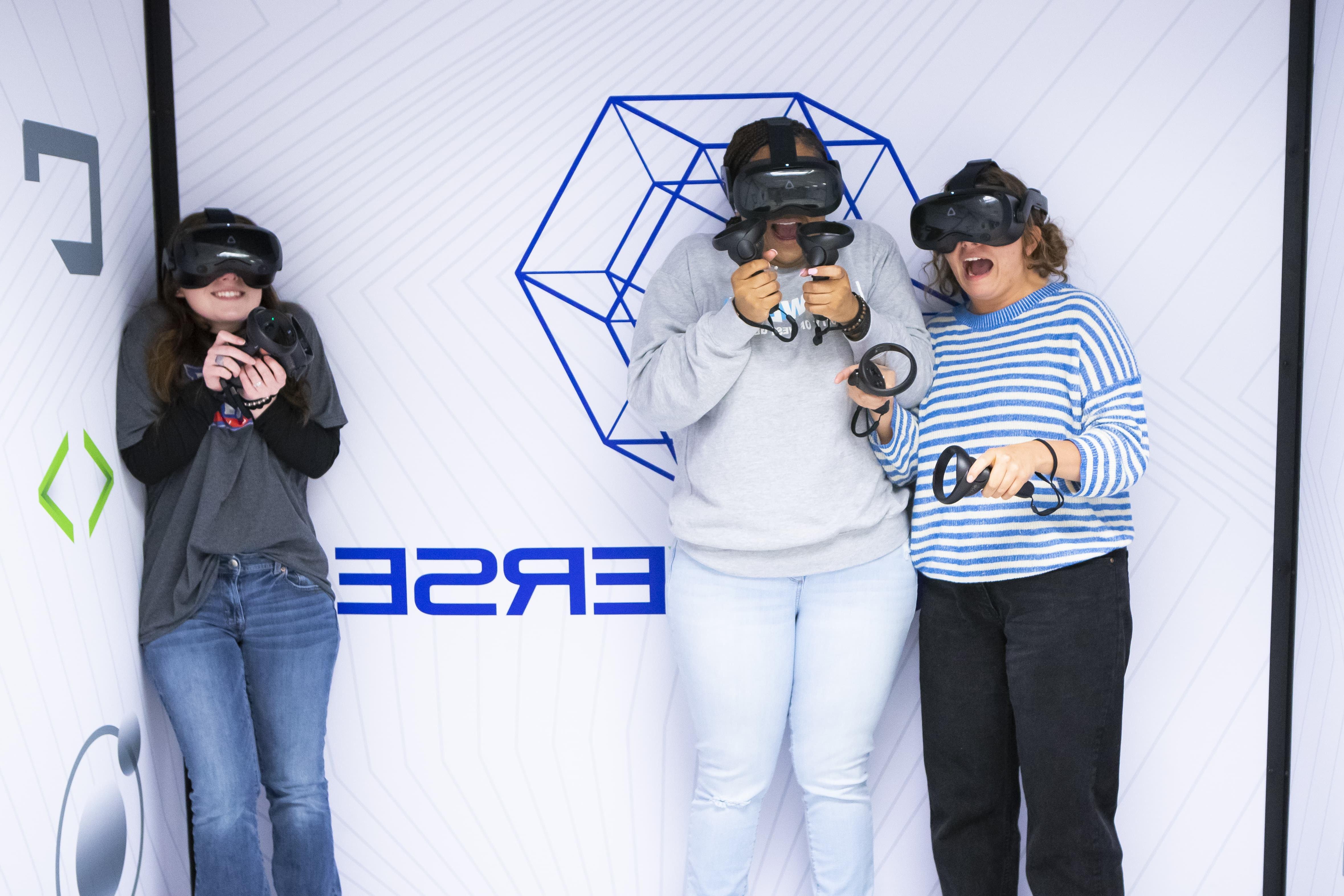 Three students look scared in a corner while playing VR.
